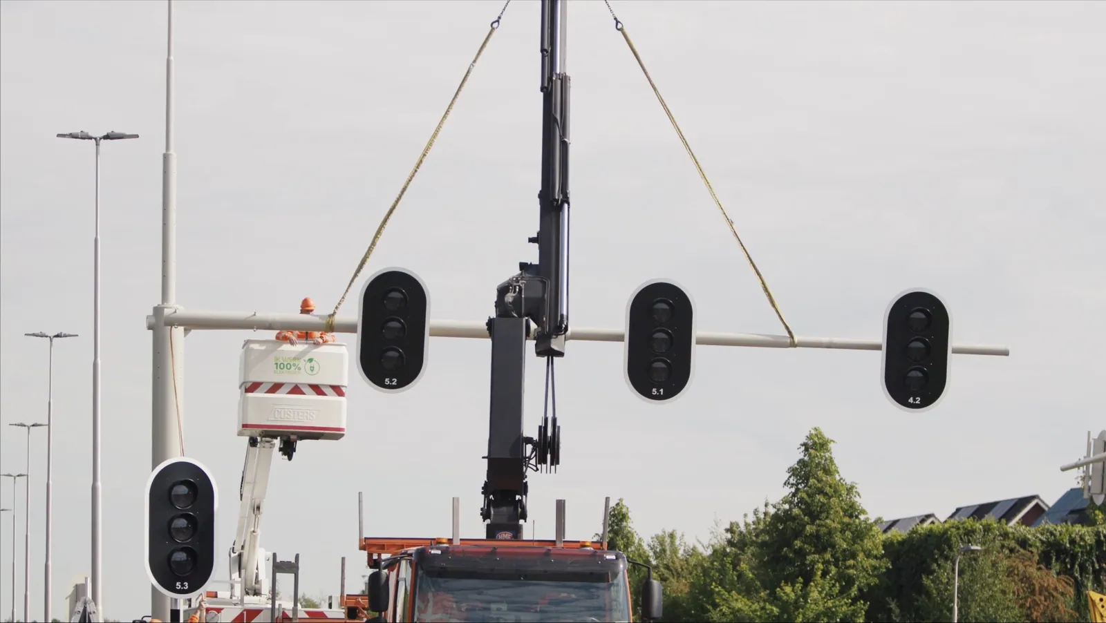 Een kraan hijst een verkeerslichtportaal op zijn plek