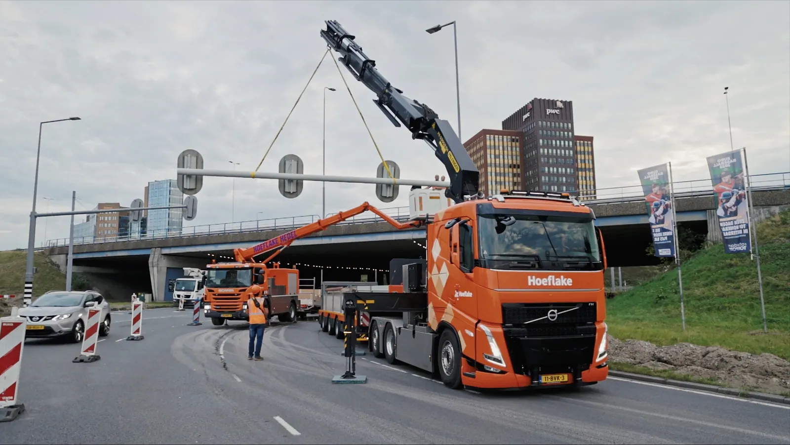 Hoeflake-kraanwagen plaatst een verkeerslichtportaal bij een viaduct