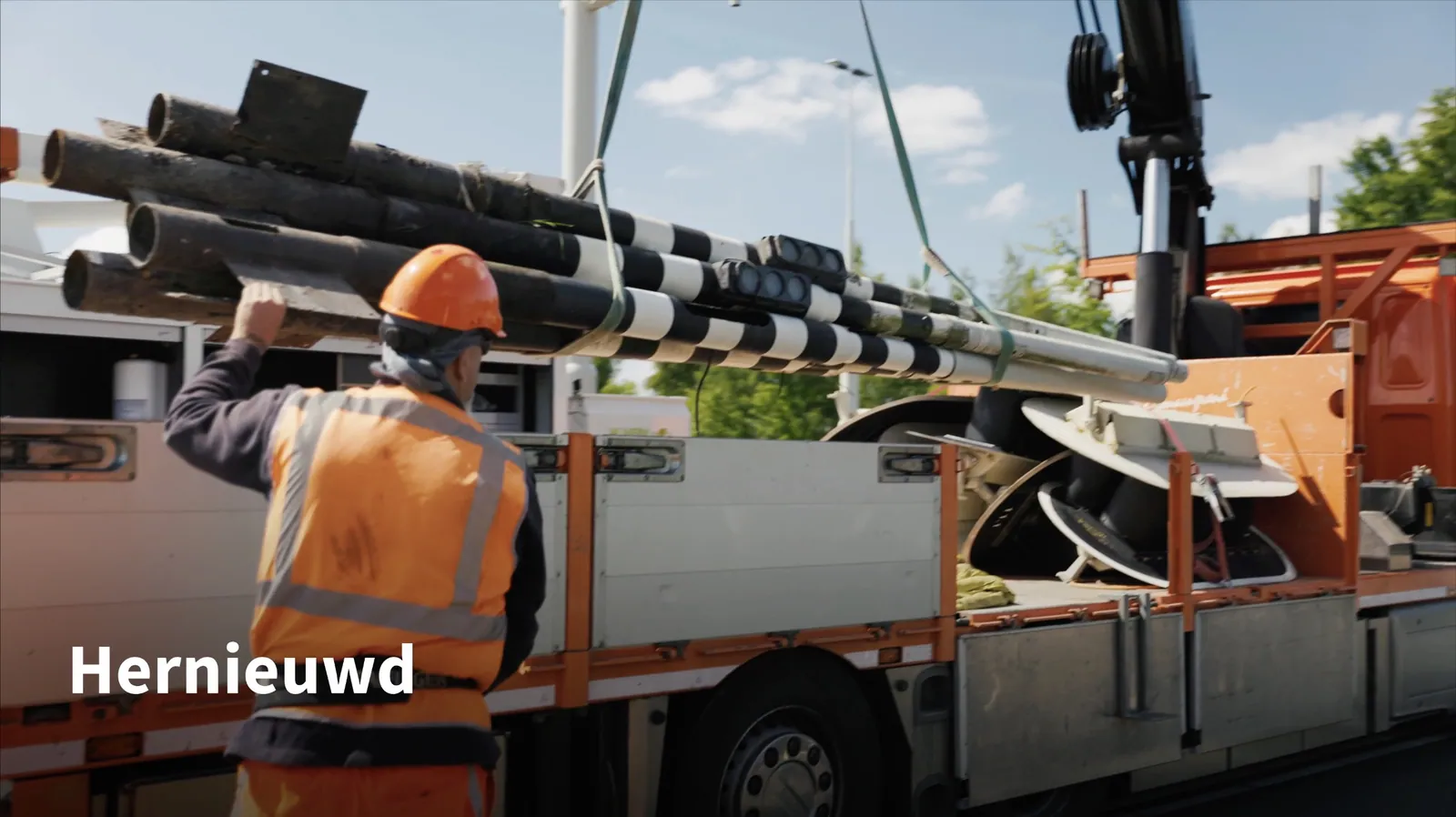 Monteur tilt lichtmasten van een vrachtwagen, met de tekst “Hernieuwd”